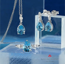 Load image into Gallery viewer, Jewelry set with blue gemstones and silver accents on a clear stand against a blue background.