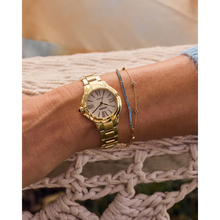 Load image into Gallery viewer, Gold watch on a wrist with a blurred background