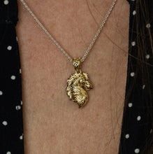 Load image into Gallery viewer, Gold horse pendant necklace on a person's neck with a polka dot background