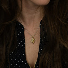 Load image into Gallery viewer, Person wearing a gold necklace with a pendant, set against a dark background.