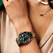 Load image into Gallery viewer, Close-up of a wrist wearing a silver watch with a green face, against a neutral background.