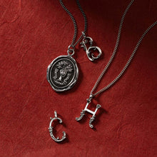 Load image into Gallery viewer, Silver necklaces with pendants on a red textured background