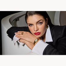 Load image into Gallery viewer, Woman in formal attire with jewelry leaning against a white wall
