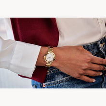 Load image into Gallery viewer, Gold watch on a wrist with a white shirt and red sleeve
