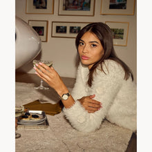 Load image into Gallery viewer, Woman in a white fur coat holding a glass in a cozy indoor setting
