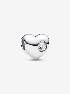 Silver heart-shaped charm with a clear gemstone on a white background