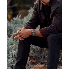 Load image into Gallery viewer, Person wearing a watch sitting outdoors with nature in the background
