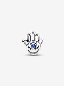 Silver hamsa hand charm with a blue gemstone on a white background