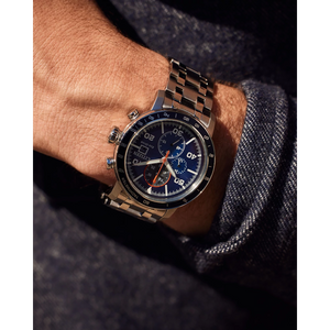 Close-up of a person's wrist wearing a silver watch with a blue face.