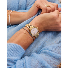 Load image into Gallery viewer, Gold watch on a wrist with a blue sweater background
