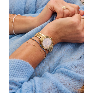 Gold watch on a wrist with a blue sweater background