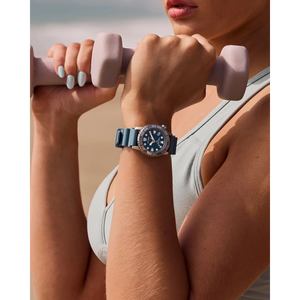 Person lifting weights with a watch on wrist, beach background