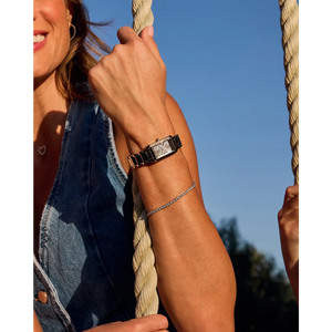Person wearing a watch on a rope swing with a clear blue sky background
