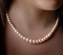 Load image into Gallery viewer, Pearl necklace being worn on a person&#39;s neck with a blurred background
