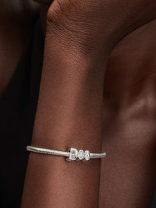 Silver bracelet with a butterfly charm on a wrist against a dark background