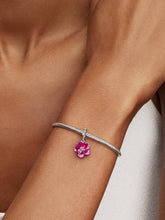 Load image into Gallery viewer, Silver bracelet with a pink flower charm on a wrist against a neutral background
