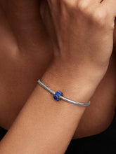 Load image into Gallery viewer, Silver bracelet with a blue gemstone on a wrist against a dark background
