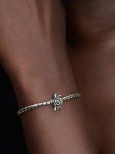 Load image into Gallery viewer, Silver bracelet with a turtle charm on a wrist against a dark background
