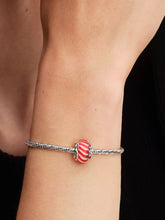 Load image into Gallery viewer, Bracelet with a candy-shaped charm on a wrist against a black background
