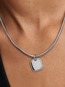 Silver necklace with a square pendant on a person's neck
