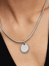 Load image into Gallery viewer, Silver necklace with a round pendant on a person wearing a black top.
