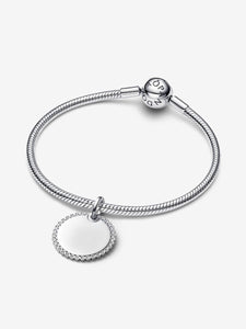 Silver bracelet with a round charm on a white background