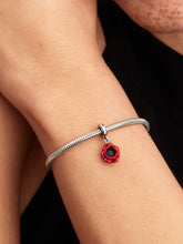 Load image into Gallery viewer, Silver bracelet with a red charm on a person&#39;s wrist against a black background
