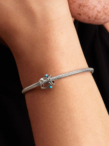 Silver bracelet with turquoise beads on a wrist against a black background