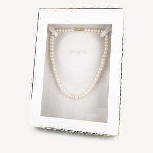Pearl necklace and earrings in a clear display box on a white background