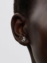 Load image into Gallery viewer, Close-up of an ear wearing a CZ crescent moon earring on a light gray background
