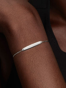 Silver bracelet on a person's wrist against a dark background