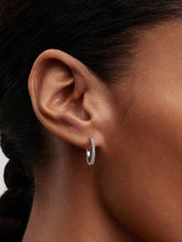 Load image into Gallery viewer, Close-up of an ear wearing a silver hoop earring with clear stones.
