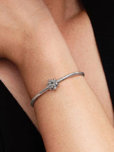 Load image into Gallery viewer, Silver bracelet with asnowflake charm on a wrist against a black background
