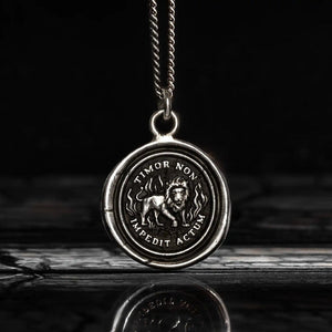 Silver pendant with lion design and engraved text on a dark background
