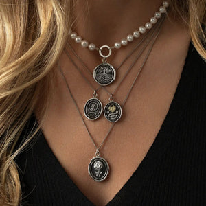 Close-up of a woman wearing multiple necklaces with various pendants.