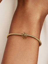 Load image into Gallery viewer, Gold bracelet with a sun design on a wrist against a neutral background
