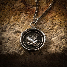 Load image into Gallery viewer, Silver pendant with a dove design on a textured stone surface
