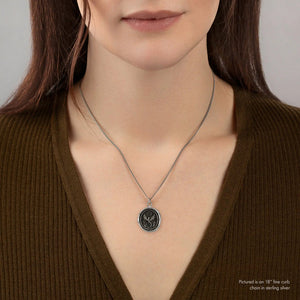 Woman wearing a necklace with a pendant on a plain background