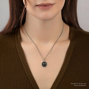Person wearing a necklace with a sunflower pendant against a neutral background